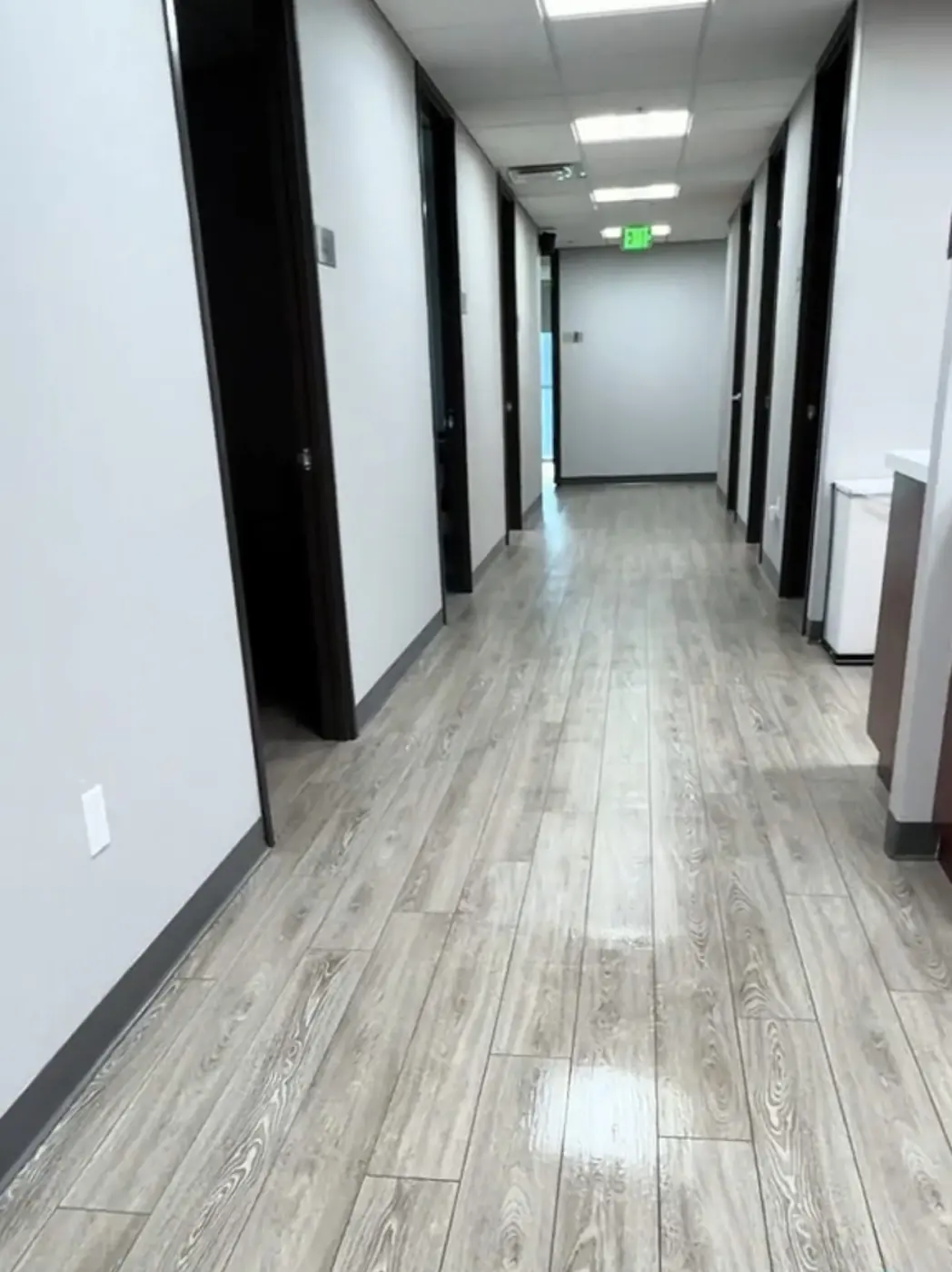 Office hallway lined with room doors, floors freshly mopped