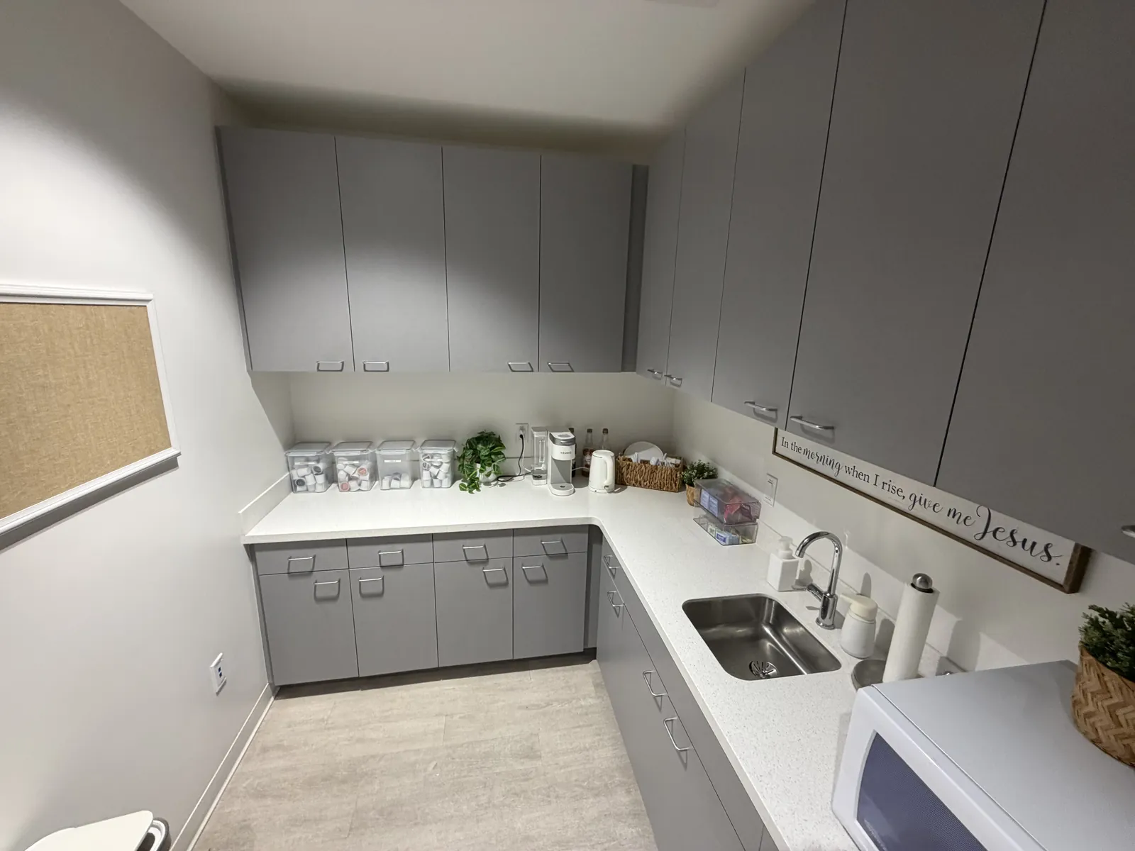 Office break room with clean counters, sink, and cabinets